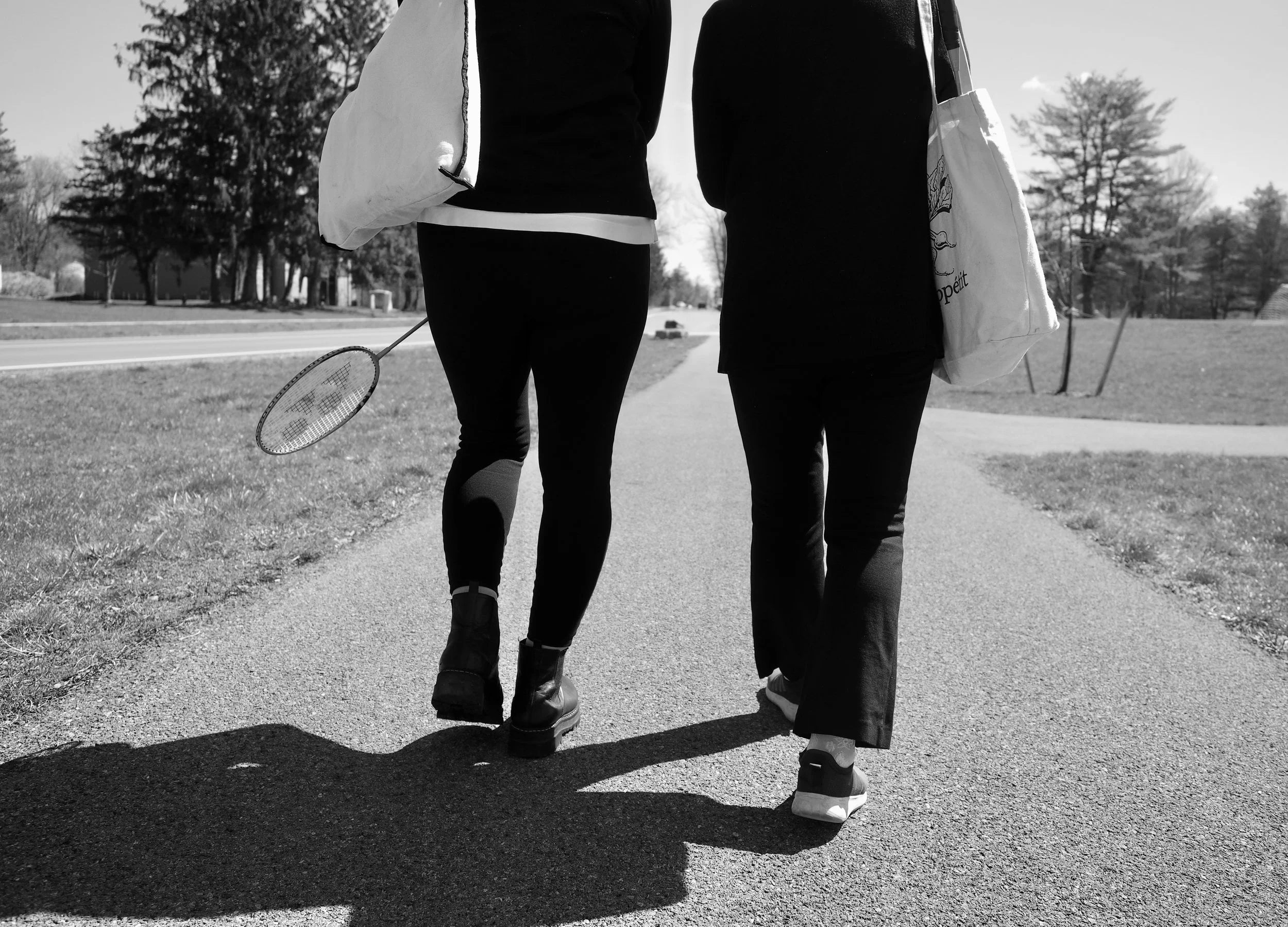 Women walking and holding bags and a tennis racket