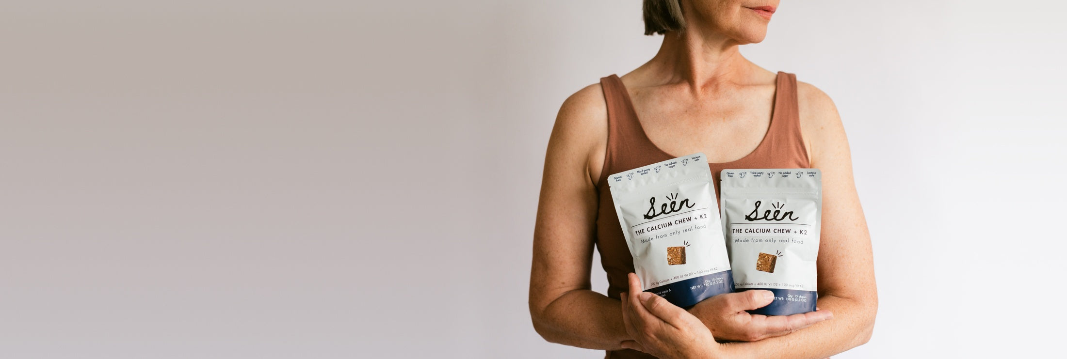 A woman holding two Seen calcium chew pouches